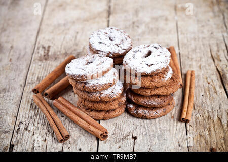 Fresh baked chocolate chip cookies with sugar powder and cinnamon sticks on wooden table background. Stock Photo