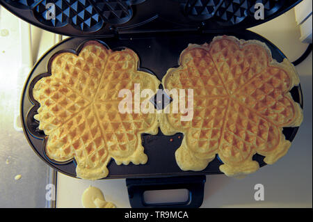 Waffle iron making heart shaped waffles. Stock Photo