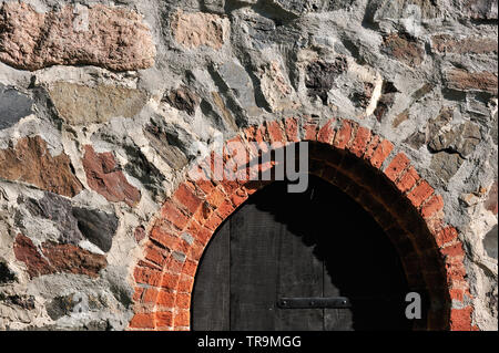 Old dark wooden door in stone wall. Stock Photo