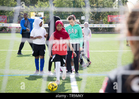 A Muslim girl with headscarf shoots a football at goal during a training session Stock Photo