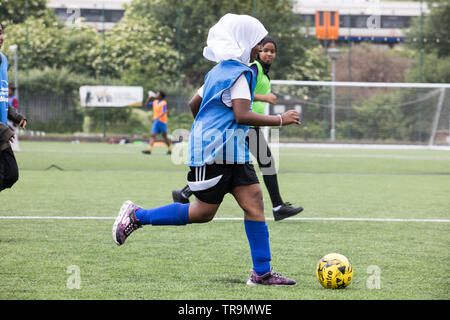 Muslim girls playing football on an astroturf training pitch. Some are wearing hijabs (headscarves). Stock Photo