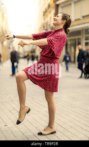 Happy woman dressed in red smiling and dancing with positive emotions Stock Photo