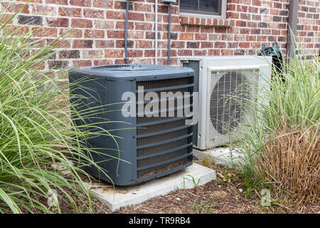 HVAC Air Conditioner Compressor and a Mini-split system together next to each other, next to a brick home. Stock Photo