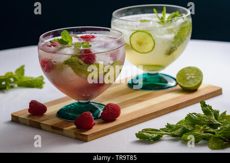Raspberry mojito and mojito rum cocktail drinks with ingredients, limes, lemons, mint, brown sugar and raspberries. Concept for restaurants, food and Stock Photo