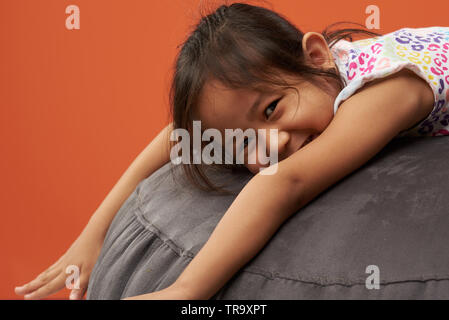 Portrait of happy asian small girl lay on soft sofa Stock Photo
