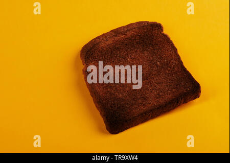 Burnt bread toast lay on yellow background isolated Stock Photo