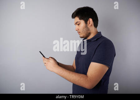 Texting on smartphone young man profile view isolated on gray background Stock Photo