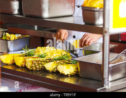 the chef  cutting pineapple. Professional kitchen, restaurant, healthy recipe. Stock Photo
