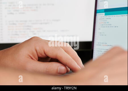Programmer hands on blurred code background close up view Stock Photo