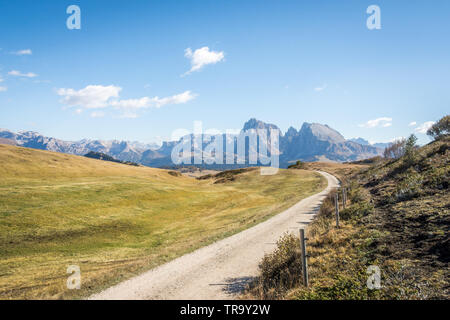 A long and winding gravel road high atop the Dolomites in northern Italy on a clear sunny day with blue skies and excellent visibility.