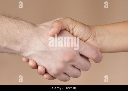Man and woman handshake isolated on brown background Stock Photo