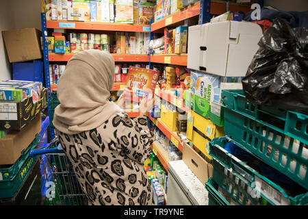 A Muslim woman with a headscarf packing bags at a foodbank Stock Photo