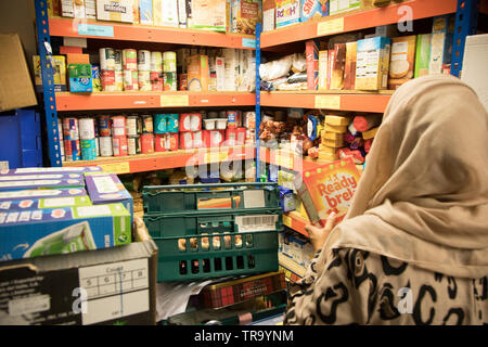 A Muslim woman with a headscarf packing bags at a foodbank Stock Photo