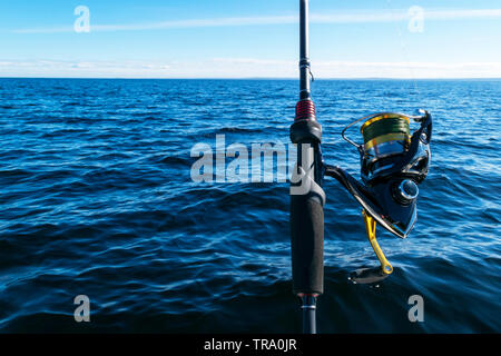 Fishing rod spinning ring with the line close-up. Fishing rod over the crystal still water. Fishing rod rings. Fishing tackle. Fishing spinning reel. Stock Photo