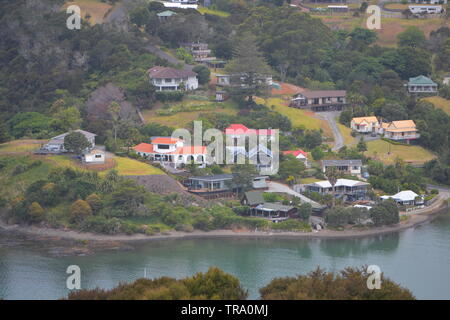 Wooden houses with yards and gravel access driveways along coast of harbor in Mangonui. Stock Photo