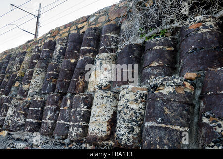 Oil drums filled with concrete act as a support structure on the Cape Peninsula coastal railway between Muizenberg and Simons Town in South Africa Stock Photo