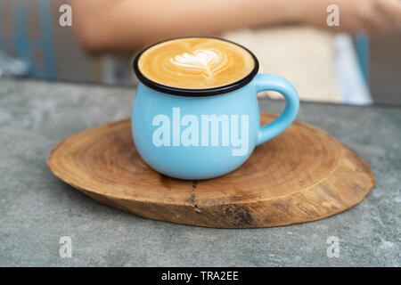 Coffee cup in blue glass on wooden plate Stock Photo