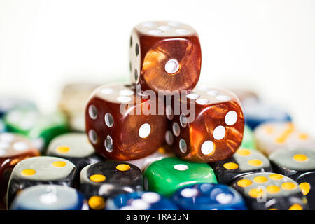 Three brown copper dice sitting on colored dice against a white background in a casino Stock Photo