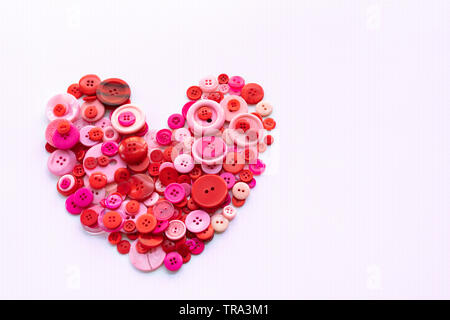 Red sewing buttons in the heart shape on white pattern background Stock Photo