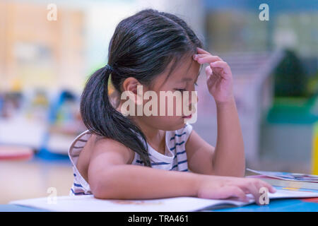 Asian cute little girl learning a book in library room, Stock Photo