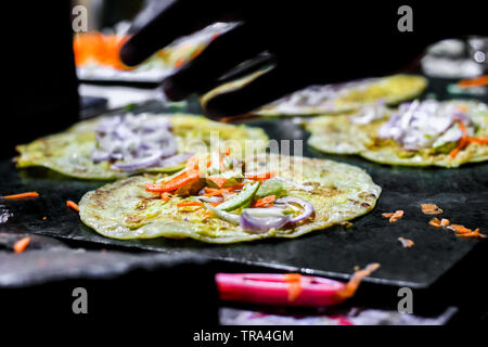 making of egg roll on a hot frying pan with oil and paratha and salad Stock Photo