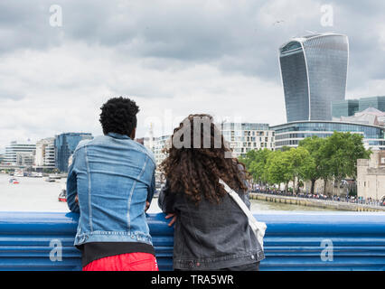 A young couple on Tower Bridge enjoying the view of the City of London's ever-changing skyline as new skyscrapers are added to the mix Stock Photo