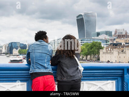 A young couple on Tower Bridge enjoying the view of the City of London's ever-changing skyline as new skyscrapers are added to the mix Stock Photo