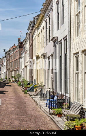 Middelburg, The Netherlands, May 30, 2019: row of facades of houses with brick facades and semi-private zones with plants, fences and benches Stock Photo