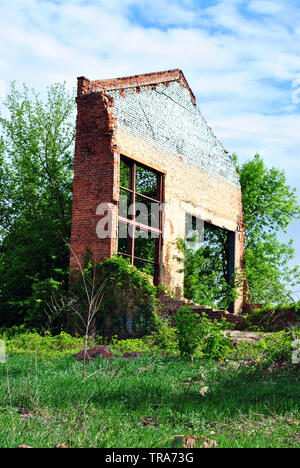 Old crumbling brick wall with window without glass, green trees and blue cloudy spring sky Stock Photo