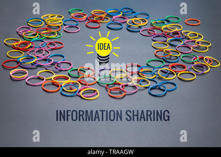 Information sharing concept, colorful rubber band with word Information Sharing and idea lighting bulb on black background Stock Photo