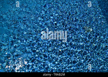 Swimming pool bottom caustics ripple and flow with waves background. Surface of blue swimming pool, background of water in swimming pool. Stock Photo