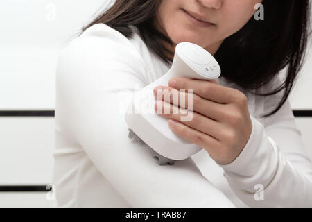 electric arm, neck and shoulder massage machine on women shoulder, closeup, healthcare and medicine concept Stock Photo
