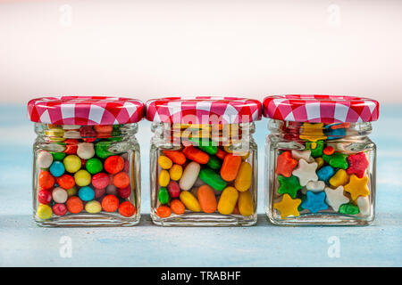 Sweet sugar candies in glass jars on brown vintage wooden background Stock Photo