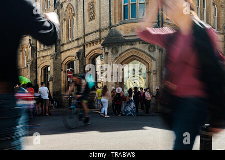 Tourists in Cambridge photograph and walk past the The Taylor Library and the Corpus Clock on the northwest corner of Corpus Christi College.