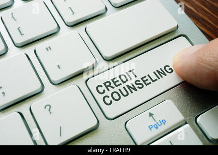 Man pushing button credit counseling on keyboard. Debt advice. Stock Photo