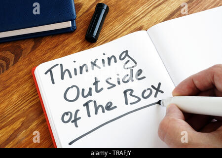 Man is writing Thinking Outside of The Box. Stock Photo