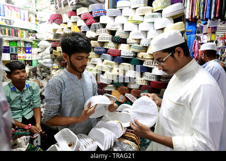 Dhaka, Bangladesh - June 01, 2019: A customer trying a tupi or prayer cap at a shop at the Baitul Mukarram National Mosque market ahead of the Eid-ul- Stock Photo