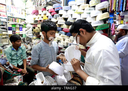 Dhaka, Bangladesh - June 01, 2019: A customer trying a tupi or prayer cap at a shop at the Baitul Mukarram National Mosque market ahead of the Eid-ul- Stock Photo