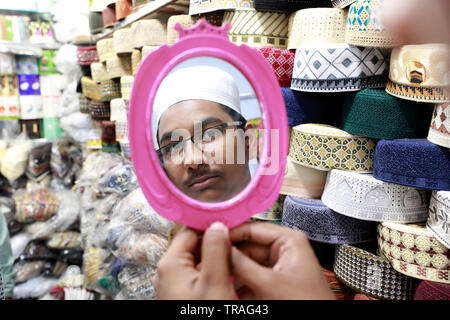 Dhaka, Bangladesh - June 01, 2019: A customer trying a tupi or prayer cap at a shop at the Baitul Mukarram National Mosque market ahead of the Eid-ul- Stock Photo