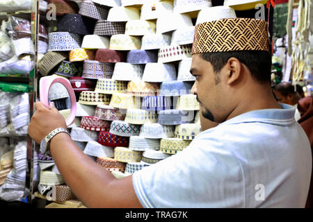 Dhaka, Bangladesh - June 01, 2019: A customer trying a tupi or prayer cap at a shop at the Baitul Mukarram National Mosque market ahead of the Eid-ul- Stock Photo