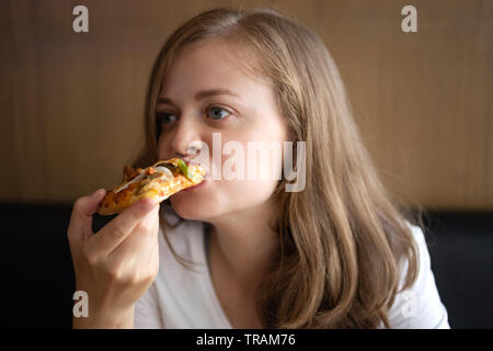Young caucasian woman eating a slice of pizza Stock Photo