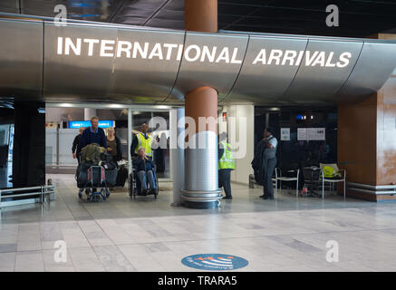 tourists and people arriving and coming through the doors of the international arrivals hall at Cape Town International Airport, South Africa Stock Photo