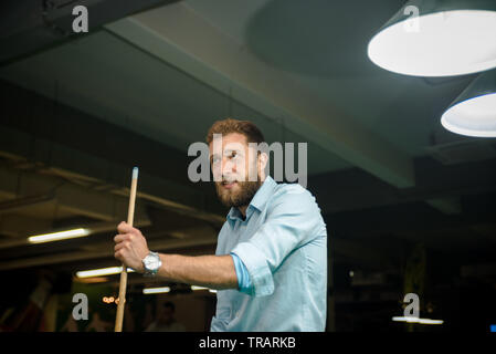 Young handsome man with beard plays billiards Stock Photo