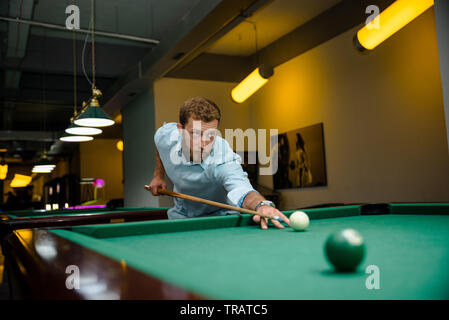 Young handsome man with beard plays billiards Stock Photo
