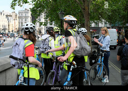 Teacher talking to French school tour group of teens students with bikes  outdoors Trafalgar Square in Central London England UK Britain KATHY DEWITT Stock Photo