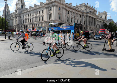 Cyclists office workers heading home after work riding bikes by Houses of Parliament & tourist buses on busy road Westminster London UK KATHY DEWITT Stock Photo