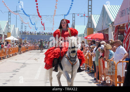 Torrevieja, Spain - June 1, 2019: Young woman wearing traditional flamenco dress riding a horse on Sevillian fair Stock Photo