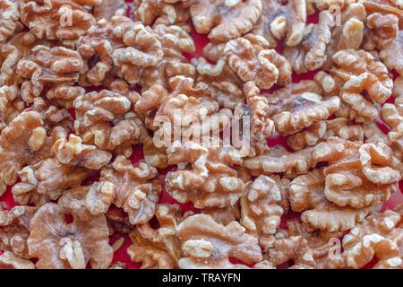 Overhead close up view of a bunch of walnuts without their shells on a red underlay Stock Photo