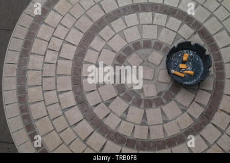 The black ceramic ashtray and the cigarette butts are extinguished on the stone table from the top. Stock Photo