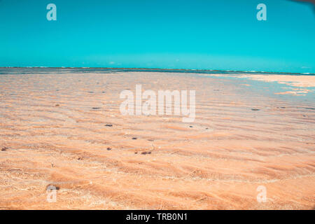 sand ridges and ripples on beach with blue water in Paraiba, Brazil - Areia vermelha Stock Photo